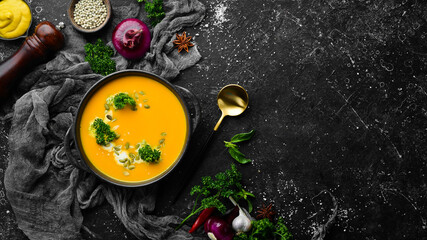 Pumpkin cream soup with pumpkin seeds in a black stone plate. Autumn menu. Diet. Top view. Free space for text.