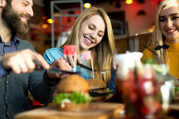 Happy smiles of friends in a restaurant while eating burgers