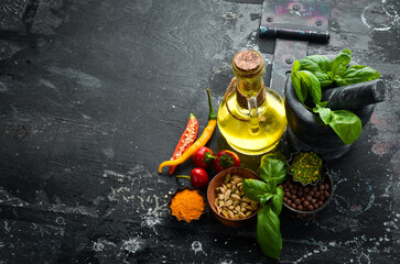 Set of spices on a black old background. Basil, oil, pepper and spices. Food background. Top view.