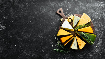 Cheese. Assortment of cheese and snacks on black stone background. Top view. Free space for your...