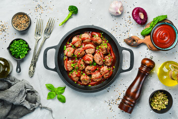 Meatballs in sweet and sour tomato sauce in a frying pan. Top view. On a stone background.