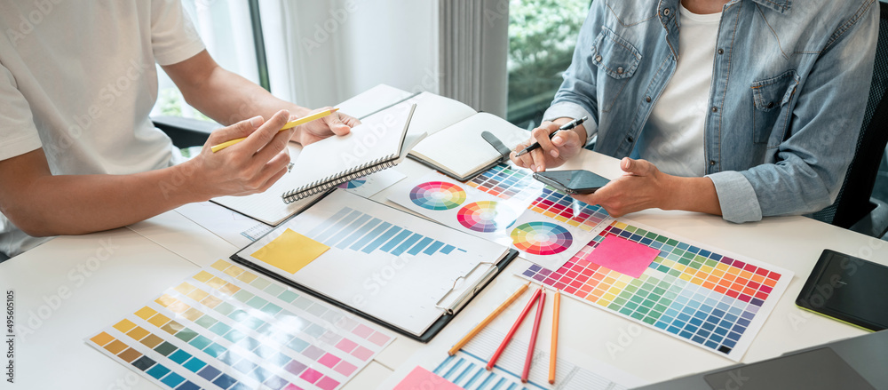 Poster Two creative graphic designer working on color selection and drawing on graphics tablet at workplace, Color swatch samples chart