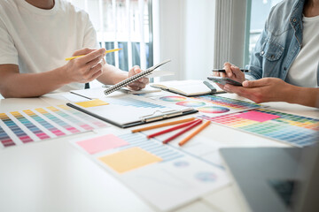 Two creative graphic designer working on color selection and drawing on graphics tablet at workplace, Color swatch samples chart