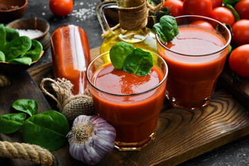 Homemade tomato juice with salt and spices in glasses. Side view. On a stone background.