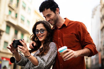 Traveling couple taking photos with camera. Loving couple walking through the city..