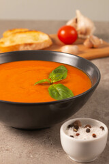 Fresh, healthy tomato soup with basil, pepper, garlic, tomatoes and bread on wooden background. Spanish gazpacho soup. Lentils and pumpkin soup.