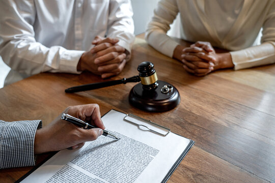 Unhappy divorce couple having conflict, husband and wife during divorce process with senior male lawyer or counselor and couple signing decree of divorce contract in lawyer's office