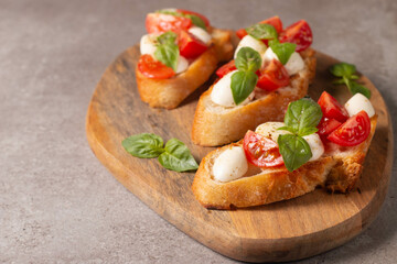 Italian tomato and cheese bruschetta. Tapas, antipasti with chopped vegetables, herbs and oil on grilled ciabatta and baguette bread.