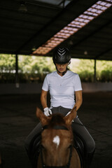 Young woman trains in horseback riding in the arena. A pedigree horse for equestrian sport. The...