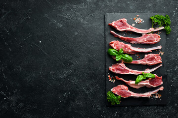 Raw fresh lamb ribs and seasonings on a slate stone plate, on a black stone background. Meat. Top...
