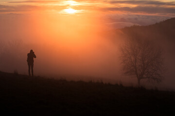 Fototapeta premium silhouette of a person standing on a mountain at sunset