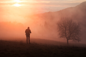 silhouette of a person standing on a mountain at sunset