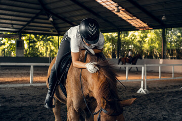 Young woman trains in horseback riding in the arena. A pedigree horse for equestrian sport. The...