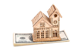 Wooden house on a stack of dollars on a white background