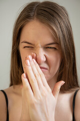 young female feels bad smell expressive face and holds hands near nose