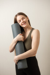 fit athletic Girl holding and hugging her yoga mat indoors