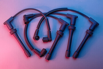 Top view of black ignition wires of a high voltage for spark plugs illuminated with blue and red...