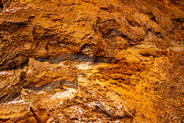 Textural sand, with  relief surface, multi-colored layers and different in size of granules, in outdoor sand career, after mining ore and sand for construction.