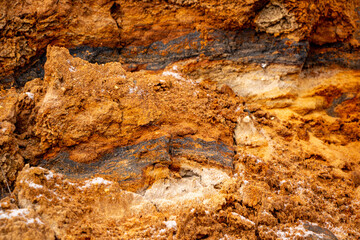 Textural sand, with  relief surface, multi-colored layers and different in size of granules, in outdoor sand career, after mining ore and sand for construction.