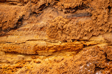 Textural sand, with  relief surface, multi-colored layers and different in size of granules, in outdoor sand career, after mining ore and sand for construction.