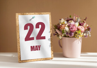 may 22. 22th day of month, calendar date.Bouquet of dead wood in pink mug on desktop.Cork board with calendar sheet on white-beige background. Concept of day of year, time planner, spring month