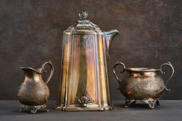 Vintage dishes, teapot, sugar bowl, jug on a dark shabby background. Selective focus