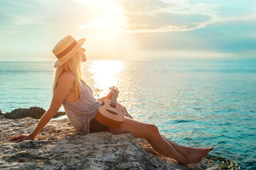 Summer Vacation. Smellingcaucasian women relaxing and playing on ukulele on beach, so happy and...