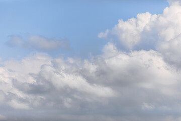 Naklejka na ściany i meble Aggressive looking grey-white big cumulus cloud on a morning soft blue sky background