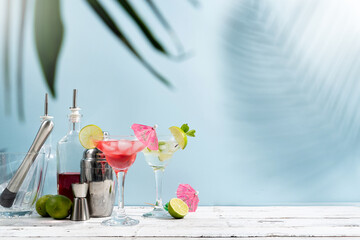 Fresh summer cocktails with strawberry, lime and ice cubes on blue background with copy space