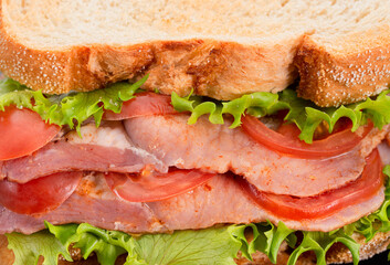 Fresh homemade BLT sandwich with double bacon, lettuce and tomato between toasted doorstep bread slices. Close up.