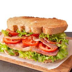 Bacon, lettuce and tomato (BLT) sandwich with double bacon between toasted doorstep bread slices. Partly isolated.