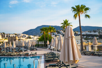 Sun loungers by the pool at dawn. Background for summer vacation concept.