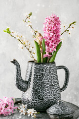 Beautiful spring bouquet of pink hyacinth flowers and plum blossom branches in an old vintage enamel teapot. Homemade decoration for Easter.