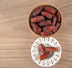 Date fruit in bowl on wooden background, top view