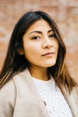 Portrait of a young woman against a brick wall