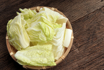 Fresh cut chinese cabbage, napa cabbage or bok choy in basket on old wooden background. 