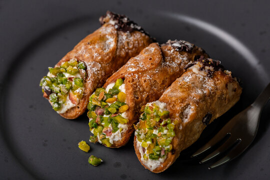 Close up of Cannoli Siciliani - traditional italian dessert stuffed with ricotta cheese cream and decorated with pistachios and chocolate.