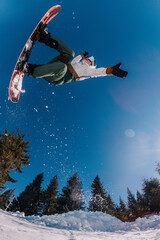 a guy jumps on a snowboard in the background of the sun and holds a front grab © Denis