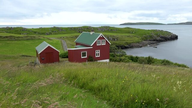 A picturesque village with red cottages on the shore of the fjord. Bright red houses on the coast of the Atlantic Ocean. Traditional scandinavian houses with grass on the roof in Iceland, Norway.