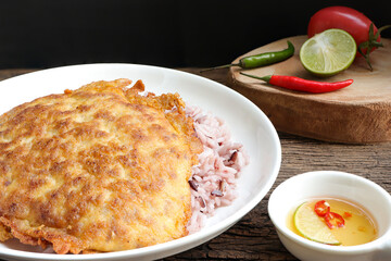 Omelette on top streamed rice. Close up of Thai omelet with rice and fish sauce on old wooden table.Thai food style.