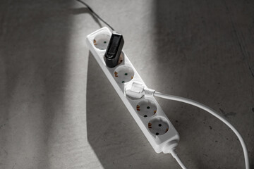 electricity, energy and power consumption concept - close up of socket with plugs and charger on concrete floor