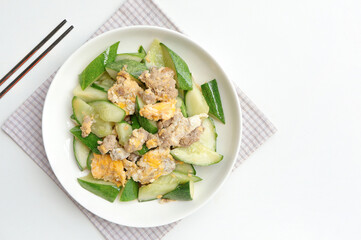 Asian stir-fried cucumber with minced pork, egg and oyster sauce in white plate. Asian food style.