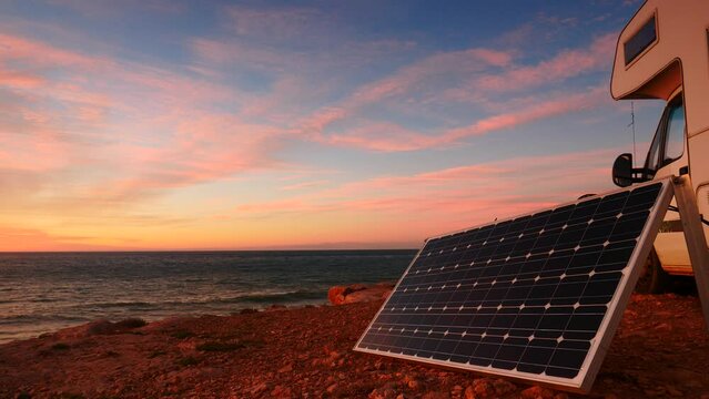 Portable solar panel at camper vehicle on sea coast. Morning light, dawning. Renewable free energy on caravan vacation.