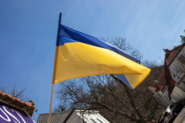 flag of ukraine against the background of the blue sky over the city liberated from the occupier, the war in Ukraine.