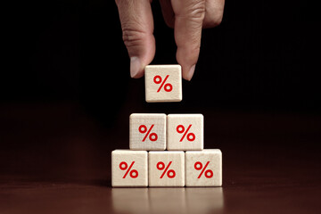 Finance and Mortgage Interest Rate Ideas Hand placed wooden cube blocks rising on top with percentage symbols up direction symbols. on a dark background.