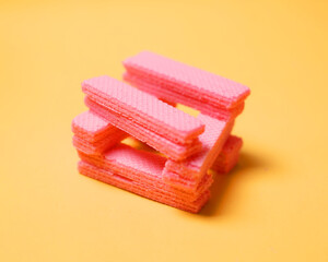 Stacks of pink wafers neatly arranged on a yellow background. Pile of taro flavored wafers. savory and crunchy snacks. snack. colorful wafers. food photography. delicious and delicious