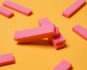 Stacks of pink wafers neatly arranged on a yellow background. Pile of taro flavored wafers. savory and crunchy snacks. snack. colorful wafers. food photography. delicious and delicious