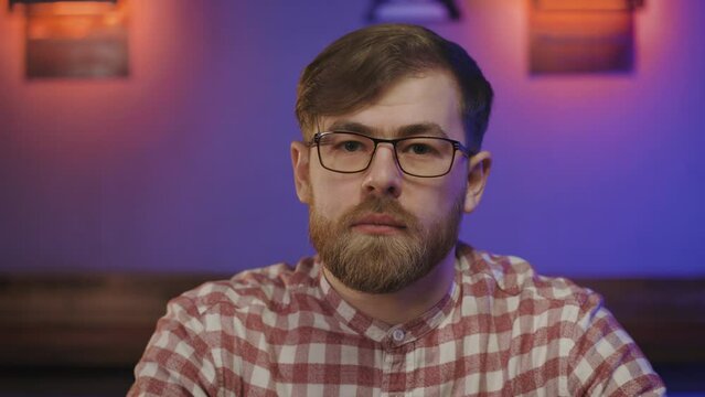 Portrait of ukrainian young man in glasses indoor. Serious man looks in to the camera with hope