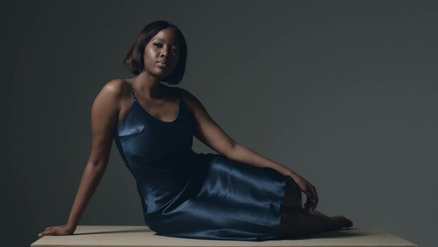 Pretty african american young girl wearing evening dress posing sitting in studio. Body positive concept. ProRes codec