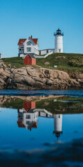 Vertical shot of the Nubble Lighthouse and its reflection in the lake in Maine, USA